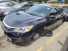 the front end of a black car that has been damaged in a parking lot with other cars