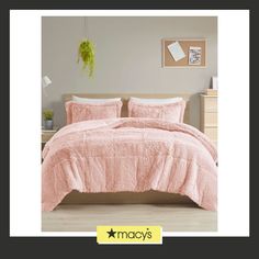 a bed with pink comforter and pillows in a room