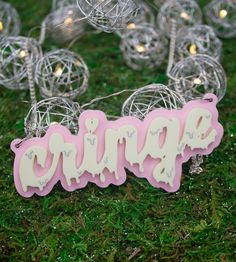 a pink and white sign sitting on top of a green grass covered field next to lights