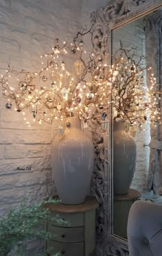 a white vase with lights in it sitting on top of a table next to a mirror