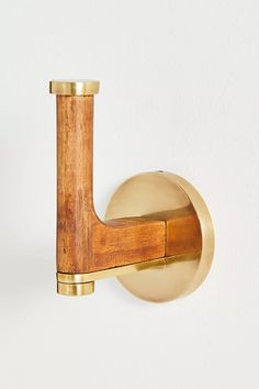 a wooden handle on a white wall with a gold colored metal object in the background