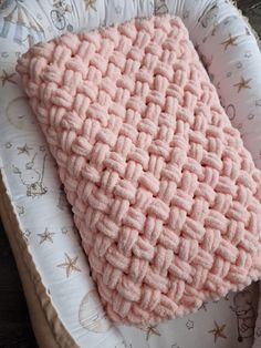 a crocheted pink blanket in a basket on a wooden table with star prints