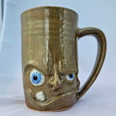 a ceramic mug with an evil face and blue eyes