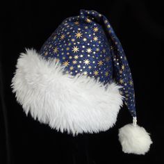 This festive Santa Claus hat is made up in a quality navy blue cotton fabric with printed metallic gold stars.  The hat is fully lined with flannel cotton fabric and has a fluffy white faux fur turn up brim.  Styling is the traditional Santa slouch stocking style hat. Proportions of the hat are generous and will fit most head sizes, ladies or gents.   *Measurement for opening for your head is 24-25" circumference and the length is 19".  There is a snowy white pompom dangle stitched on the top. *NOTE* The size of this hat is posted in the description. It is important to check your size requirements before you order.  If you think you will need a larger or smaller size keep in mind this hat is handmade and customizing may be available. Just send me a message as to your requirements. Closet Cosplay, Navy Blue And Gold, Santa Claus Hat, Christmas Costume, Santa Claus Christmas, Christmas Costumes, White Faux Fur, Costume Hats, Blue And Gold