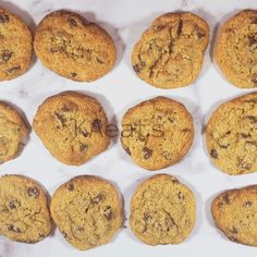 twelve chocolate chip cookies on a white marble surface