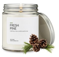 a candle with pine cones on it next to a jar of fresh pine scented candles