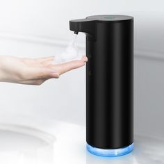 a person's hand holding a soap dispenser