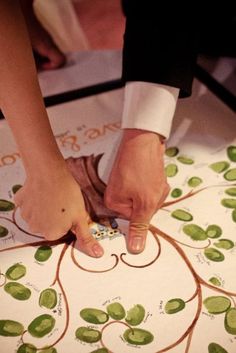 a person cutting paper with scissors on top of a table covered in green leaf designs