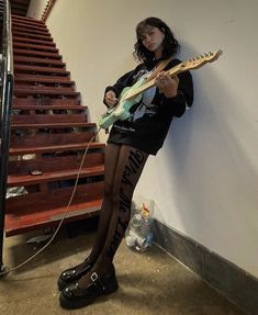 a woman in tights is holding a guitar