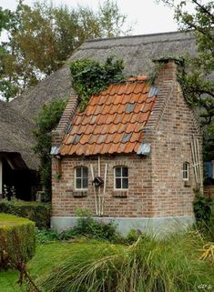 an old brick house with a thatched roof