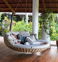 a woman laying in a hanging chair on a porch