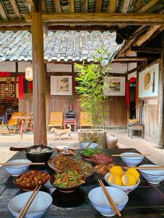 a table topped with lots of bowls filled with different types of food and chopsticks