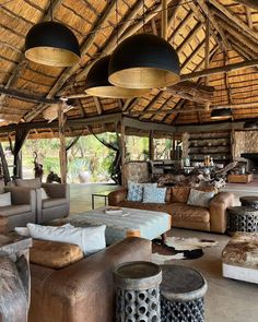 a living room filled with lots of couches and chairs under a thatched roof