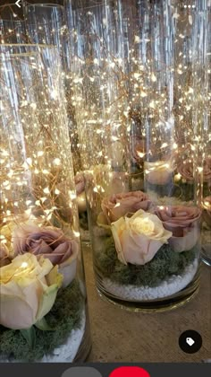 some glass vases with flowers and lights in them