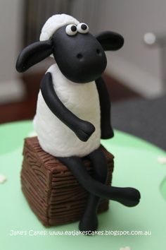 a cake made to look like a sheep sitting on top of a piece of wood