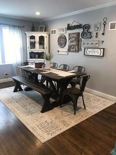 a dining room table with chairs and a bench in front of the wall that has pictures on it