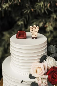 a wedding cake decorated with flowers and two figurines sitting on top of it