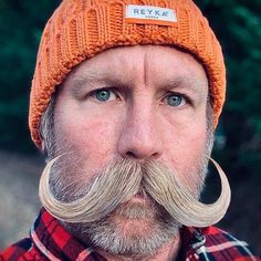 a man wearing an orange hat with a fake moustache