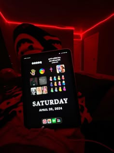 a tablet with the words saturday on it sitting in front of a red lit room