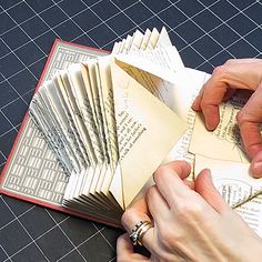 a person is making an origami book out of old books with scissors and paper