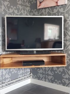 a flat screen tv sitting on top of a wooden entertainment center next to a wall