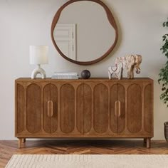 a living room with a round mirror on the wall next to a wooden cabinet and potted plant