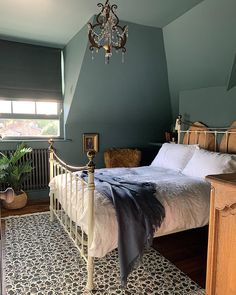 a bed room with a neatly made bed and a chandelier hanging from the ceiling