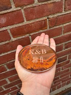 a person holding up an old rusted metal object in front of a brick wall