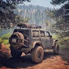 a jeep is parked on the side of a dirt road with trees in the background