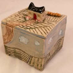 a wooden box with a black and white cat sitting on it's top, surrounded by beads