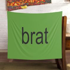 a green banner with the word brat on it in front of a white brick wall