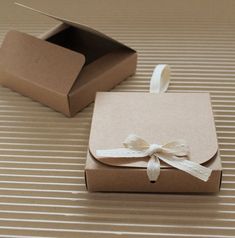 a brown box with a white ribbon tied around it and an empty cardboard box next to it