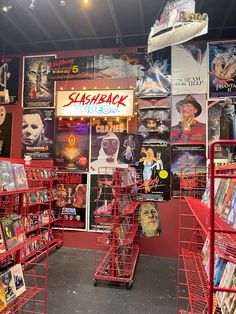 the inside of a movie store with many movies on display in red carts and posters behind them