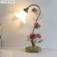 a lamp that is on top of a table next to a book and some flowers