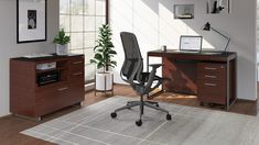 an office area with a desk, chair and computer on top of a rug in front of a window