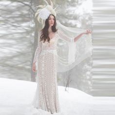 a woman in a white dress is standing in the snow with her arms spread out