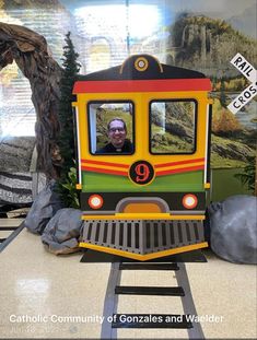 a man is looking out the window of a colorful train car in front of a mountain scene