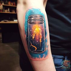 a man's arm with a jar on it that has a rocket ship in it