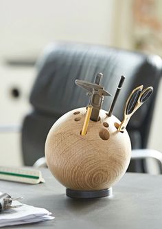 a wooden holder with scissors and scissor in it sitting on a table next to a chair