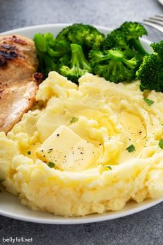 a white plate topped with mashed potatoes and broccoli next to a fork