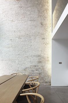 a wooden table and chairs in front of a brick wall with lights on the ceiling