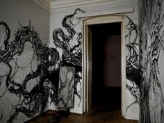 an open door leading into a room with black and white artwork on the wall behind it