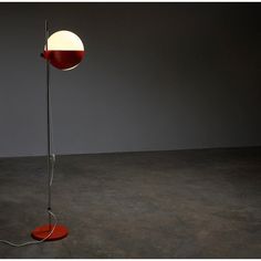 a floor lamp with a red base and a white ball on the top of it