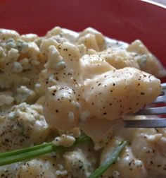 a fork with some food on it in a red bowl and green beans, asparagus and cauliflower