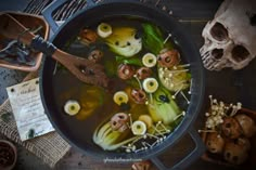 a pot filled with soup next to skulls and other items on top of a table