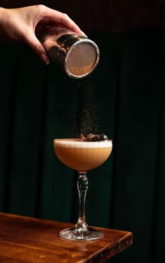 a person pouring something into a glass on top of a table