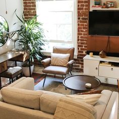 a living room filled with furniture and a flat screen tv mounted on a wall next to a window