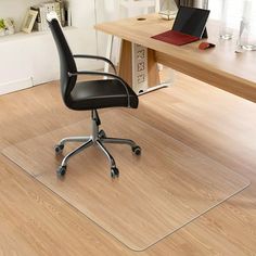 an office chair with a clear desk mat on the floor next to a laptop computer