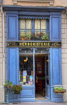 a store front with blue shutters and flower boxes on the window sill in front