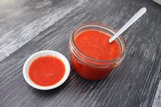 a jar of tomato sauce next to a small white bowl with a spoon in it